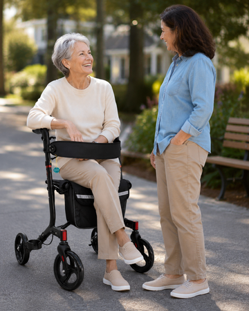 Senior woman seated on the rollator seat talking with a companion outdoors