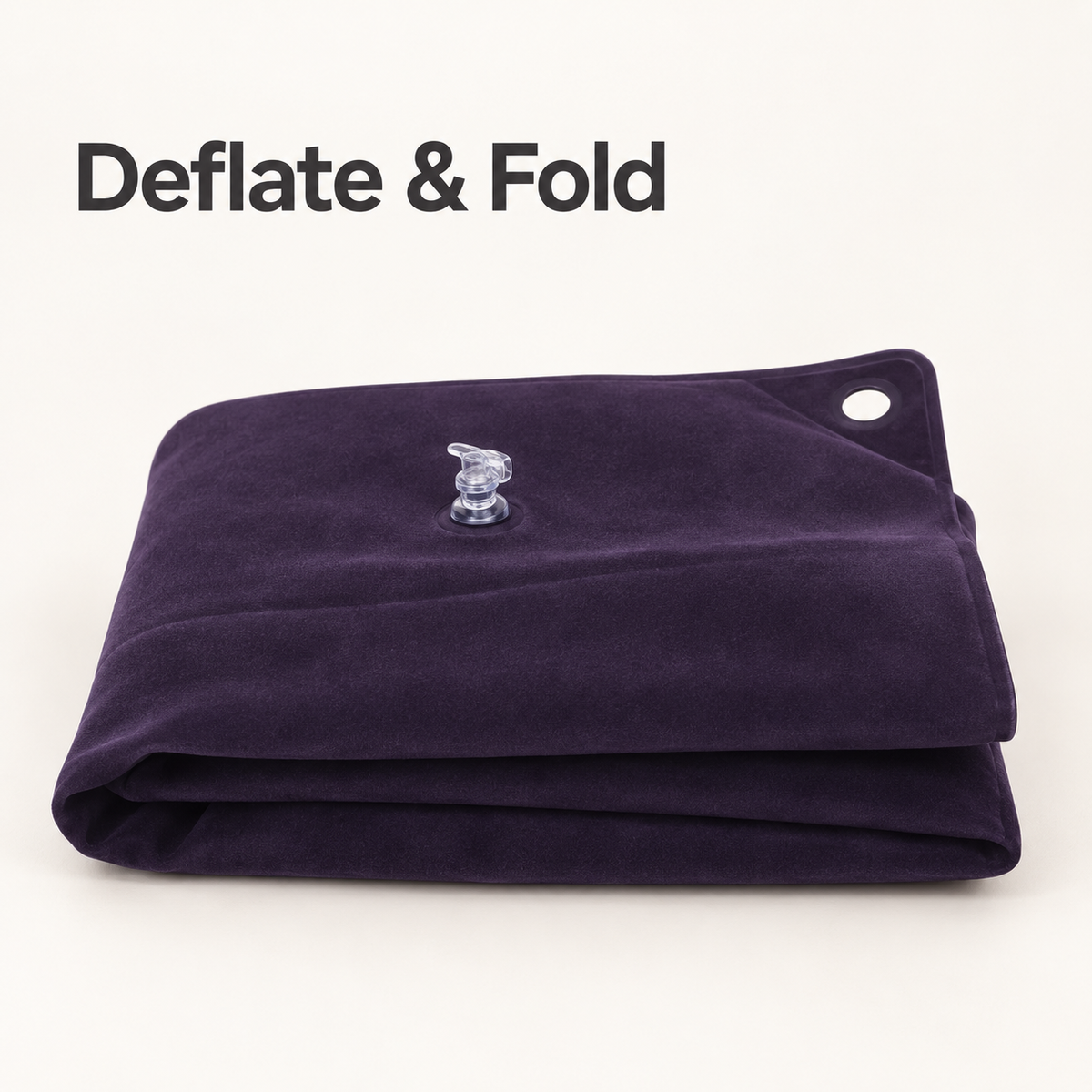Dark purple commode cushion deflated and folded for storage, with its clear air valve visible.